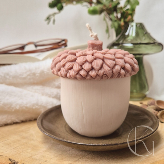 Handgemaakte eikel kaars in bruin/witte kleur, gestyled met een opengeslagen boek, bril en plaid voor een cozy herfstgevoel