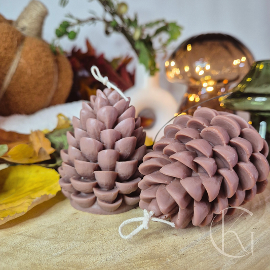 handgemaakte dennenappelkaars, warme herfstdecoratie op tafel naast herstbladeren