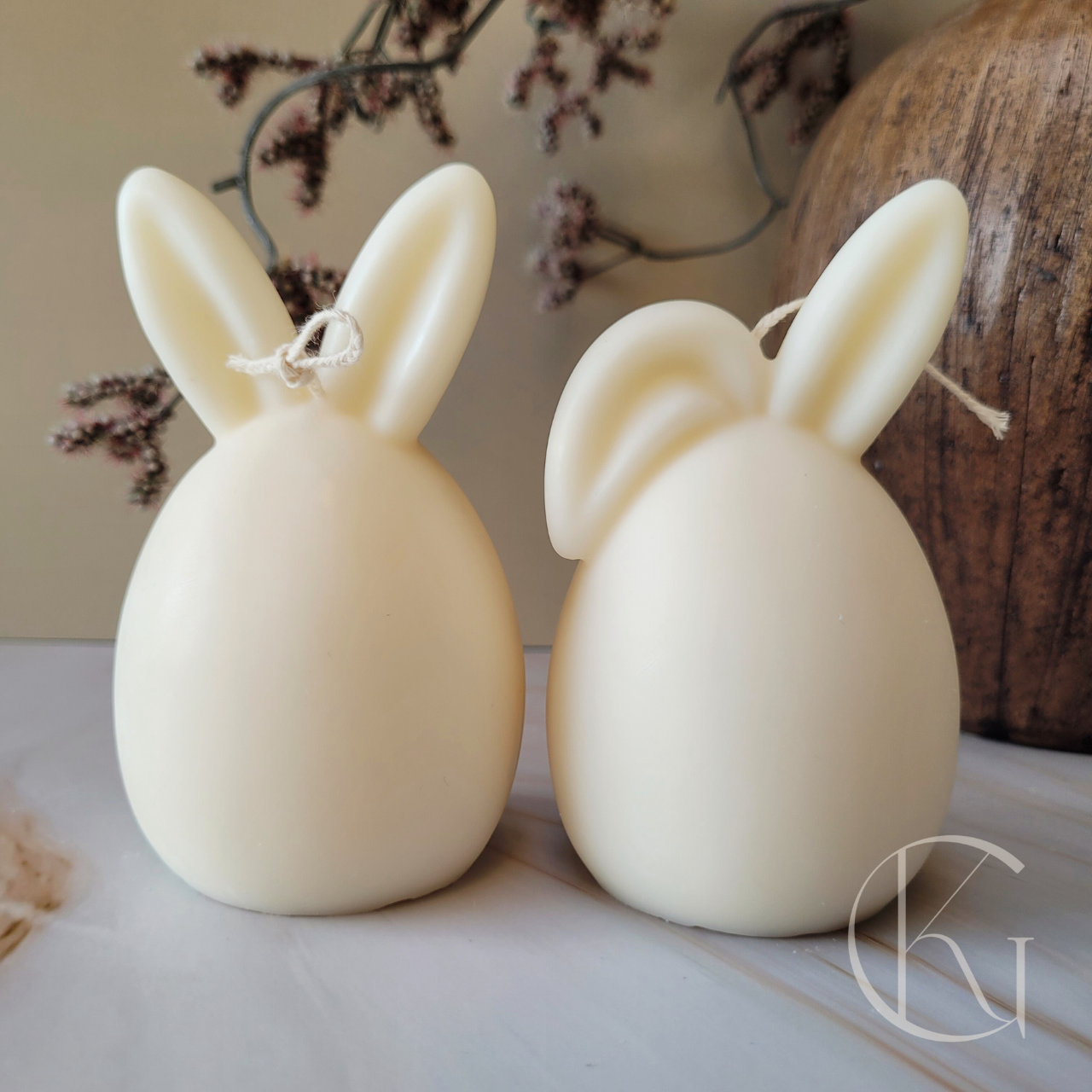 Twee handgemaakte ei-kaarsen met oortjes voor Pasen, één met twee rechtopstaande oren en één met één gebogen oor, verkrijgbaar los of als set, perfecte paasdecoratie.